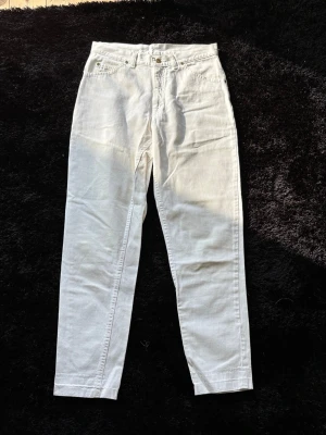 Vita raka jeans med hög midja (Lee) - Säljer ett par vita jeans med rak passform och hög midja. Jeansen har klassiska fickor både fram och bak och är sydda i ett mjukt, lite tjockare bomullstyg. Perfekta för en clean och fräsch look.