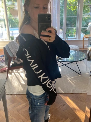 Svart hoodie från Calvin Klein - Supersnygg svart hoodie från Calvin Klein med dragkedja och snören vid halsen. Passar perfekt med ett par jeans att ha på en vardag. Jag säljer den pågrund av att den inte passar min stil längre❤️