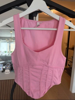 Rosa korsett-topp - Snygg rosa korsett-topp med breda axelband och markerade sömmar framtill som ger en cool siluett. Toppen har en v-ringad halsringning och är tillverkad i mjukt bomullsmaterial. 