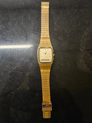 Klocka - Stilren guldfärgad klocka från Citizen med både analog och digital display. Klockan har en rektangulär urtavla, metallarmband och flera knappar på sidan för olika funktioner. Perfekt accessoar för dig som gillar retrostil. Allt fungerar prefekt behövs bara ett nytt batteri. Priset kan diskuteras