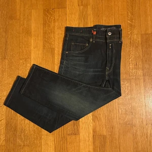 Replay Jeans Masig 32/32, passar som L26. - Säljer dessa tvärfeta replay jeans med riktigt snygg wash och sköna fades i extremt bra skick🤩. Har SELVEDGE söm på (Bild 2). De röda detaljerna på jeansen ger dem en mycket chill men sofistikerad look. Modellen är ”MASIG”, en mycket unik och eftertraktad STRAIGHT FIT modell då de inte säljs nya längre. Storlek: W32 L32, men modellen är kort vilket gör att de sitter som W32 L26. Längd innersöm: 60cm Säljer då de tyvärr inte passar mig. // Emil
