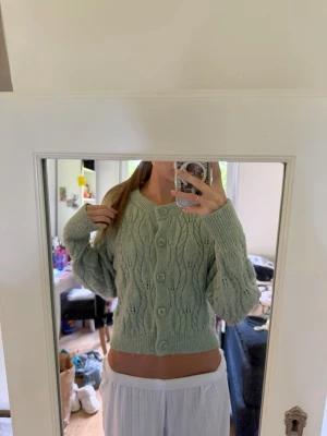 stickad kofta - Superfin ljusgrön stickad kofta med stora knappar framtill och ett vågigt mönster från Zara. Koftan är croppad, har långa ärmar och ribbade muddar. Perfekt att slänga över en topp för en chill look. Har knappt använts, inga skador!💚