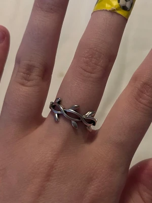 Snygg silverfärgad bladring - Unik ring i silverfärgad metall med ett flätat mönster av små blad runt hela ringen. Perfekt för dig som gillar naturinspirerade accessoarer och vill ha något som sticker ut lite extra.