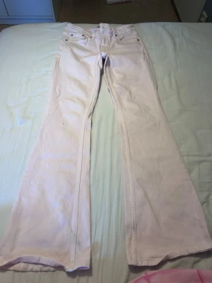 Ljusrosa bootcut jeans - Säljer ett par ljusrosa jeans med bootcut-modell och klassisk femficksdesign. Jeansen har hällor för skärp och stängs med knapp och dragkedja. Perfekta för dig som vill ha en soft och trendig look.