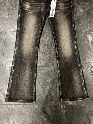 Purple Brand Jeans Flared - 🖤 PURPLE BRAND JEANS – RHINESTONE EDITION 🖤 Style No. P001 — Slim Fit, Low Rise, Slim Leg Size: 34 (US)  ✔️ Grå/svart acid wash denim ✔️ Rhinestone/kristall-detaljer längs sidosömmarna på båda benen ✔️ Distressed slitningar vid knä och fåll ✔️ Lined back pockets ✔️ Hidden back pocket rivets ✔️ Corded belt loops + reinforced bartacking ✔️ Helt nya med lappar — aldrig använda  📦 Snabb frakt, rökfritt hem 💬 Bundle-rabatt vid fler köp — hör av dig! 