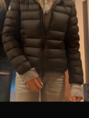 Colmar jacka  - Säljer en svart pufferjacka med huva och dragkedja framtill. Jackan har två fickor med dragkedja och quiltad design. Perfekt för kalla dagar och riktigt skön att bära. Klassisk look med diskret logga på ärmen. Har ett litet hål som är tejpat så syns knappt.