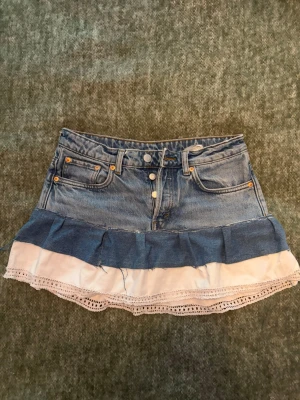 Jeanskjol med volang och spets - Säljer en egen gjord jeanskjol med volang. Har inte använt eller tvättats. Vet ej hur kvaliteten är under längre tid eftersom sömmarna gjorts fort, annars jättefin☺️