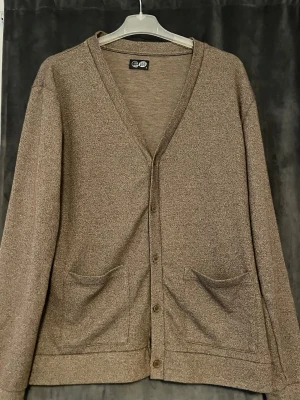 Beige kofta  - Mysig beige kofta med v-ringning och knäppning framtill. Två stora fickor framtill och långa ärmar. Perfekt för lager på lager och enkel att matcha med olika outfits. Materialet känns mjukt och bekvämt.