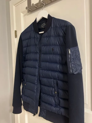 Polo Ralph Lauren Performance Hybrid Down Bomber Jacket - En del av Polo Ralph Laurens Fall/Winter 2017 kollektion. Nypris på varan 3495kr, storlek S. Bra skick, det ända som kan anses bristande är att den är lite nopprig på insidan av ärmarna se bild 6, likadant på andra ärmen. Perfekt nu inför Höst!