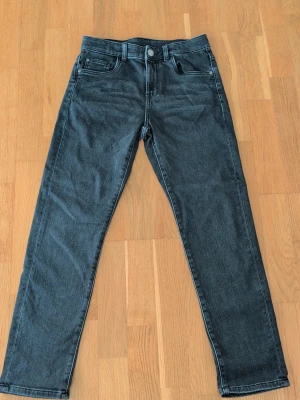 Svarta raka jeans med fem fickor - Snygga svarta jeans med rak passform och klassisk femficksdesign. Jeansen har bälteshällor, knapp och dragkedja framtill samt bakfickor med diskreta sömmar. Perfekta för en stilren och enkel look. 