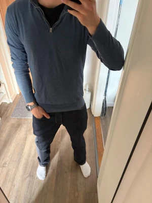 Blå långärmad tröja med half zip - Mörkblå långärmad tröja med half zip i halsen. Tröjan har en enkel och stilren design, perfekt för en avslappnad look. Passformen är normal och materialet ser ut att vara mjukt och bekvämt.