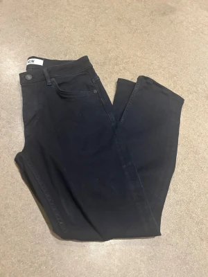  Neuw jeans  - Snygga jeans från Neuw med rak/slim passform och klassisk femficksdesign. Jeansen har en stilren look med knappar framtill samt diskret logga på bakfickan. Perfekta för en clean och enkel stil. Strl 29/30. Modell Lou. Ordinarie pris ca 1700:-. Färgen upplevs riktigt mörk blå till svart. 