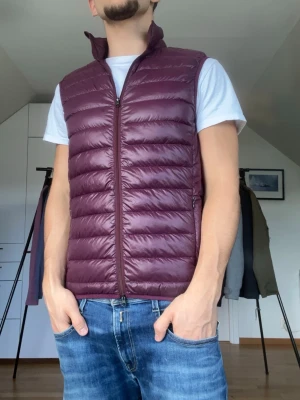 Vinröd Riley dunväst  - Vinröd dunväst från Riley. Strl S. Inga defekter. Modellen är 178 cm och väger 77 kg. Hör gärna av dig vid frågor!