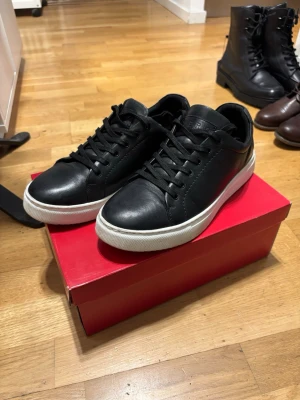 Svarta sneakers WERA - Stilrena svarta sneakers i läder med klassisk vit sula och svarta skosnören. Snygg och enkel design som passar till det mesta. Lågt skaft för en clean look och bekväm känsla. Perfekta för dig som gillar minimalistisk stil. Använt dom ett fåtal gånger, vid frågor eller om ni vill ha fler bilder är det bara att höra av sig!