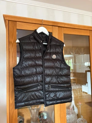Svart dunväst från Moncler - Snygg svart dunväst från Moncler med quiltad design och hög krage. Använt typ 3 gånger sen bara hängt i garderoben 🙃❤️ pris kan diskuteras 