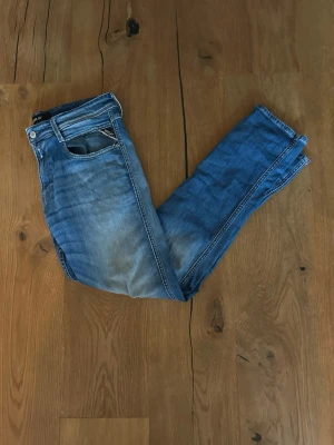 Replay anbass  - Snygga blå slim fit jeans med lätt slitna detaljer och klassisk femficksdesign. Jeansen har en ljusare tvätt framtill och en bakficka med dekorativ söm. Tillverkade i denim med en skön stretch för extra komfort.
