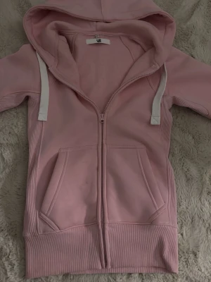 Russe merch hoodie Rosa - Säljer en ljusrosa Russe merch hoodie då den inte kommit till användning. Använd endast 1 gång och den har en pytteliten fläck bredvid dragkedjan som man ser på bilden men den går nog helt bort i tvätten. Jag inte har tvättat den själv då jag ville behålla tröjans nyskick. Nypris:750kr