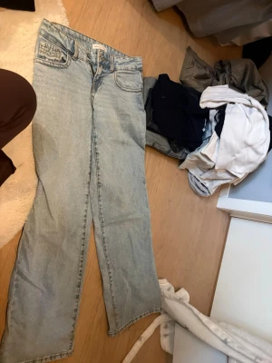 Ljusblå wide jeans med låg midja - Säljer ett par ljusblå jeans med rak passform och låg midja. Jeansen har klassiska fem fickor och bälteshällor. Materialet är denim i bomull. Lite slitningar vid benen(se bild 3) Dem är smutsiga vid benen men kommer såklart tvätta jeansen innan jag fraktar. 