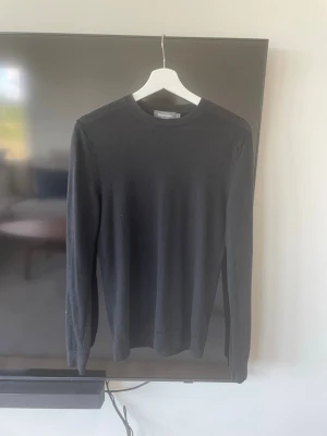 Svart långärmad tröja från Dressmann - En stilren svart långärmad tröja med rund hals. Tröjan har en enkel och klassisk design utan synliga detaljer eller mönster. Perfekt att matcha med olika outfits och passar året runt. Liten slitning som man kan se på tredje bilden men ingenting man märker av vid användning. Tveka inte på att höra av dig vid frågor!