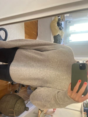 Beige oversized stickad tröja - Mysig beige stickad tröja med hög hals och avslappnad, oversized passform. Tröjan har långa ärmar och ribbade muddar vid hals, ärmslut och nederkant. Perfekt för lager på lager och chill dagar.