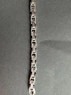 Kraftigt silverfärgat länkarmband - Säljer ett stilrent armband i silverfärgad metall med robusta, rektangulära länkar. Armbandet har en modern och chunky design med karbinlås. Perfekt accessoar för dig som gillar en tuffare stil.