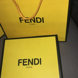 Fendi bälte med FF-logo - Säljer ett snyggt Fendi bälte med klassisk FF-logo i svart metall. Bältet har ett mönstrat band i grått och svart och levereras. ingen förpackning följer med bara bältet . Perfekt accessoar för att lyfta din outfit.