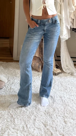 Ljusblå bootcut jeans - Säljer ett par ljusblå bootcut jeans från urban outfitters med dubbla knappar i midjan. Storleken är W26 L32. Jeansen har en lätt tvättad look och är tillverkade i denim med lite stretch för skön passform. 
