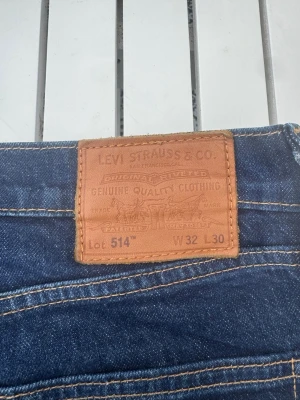 Levi's 514  - Klassiska blå jeans från Levi's modell 514 med rak passform. Jeansen har två bakfickor med den ikoniska V-sömmen och ett brunt läderpatch bak i midjan. Tillverkade i slitstark denim med kontrastsömmar och normal midja.