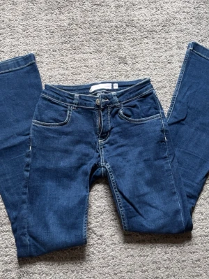 Lågmidjade jeans - Mörkblå lågmidjade utsvängda jeans från Subdued. Köpta i London 2022. De hade fold-over fickor med en knapp baktill som jag sprättat bort (se sista bild) Små i storleken. Nypris 700kr