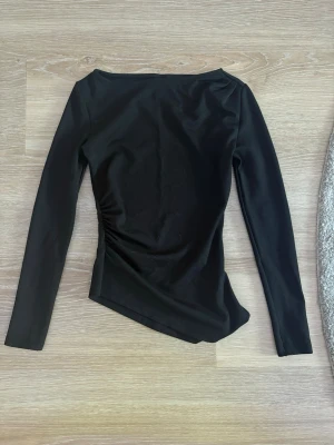 Svart långärmad topp med asymmetrisk kant - Älskar denna tröjan men var tyvärr för liten I armarna, I storlek xs, helt ny utan lapp from Gina tricot, svart asymmetrisk kant, som sagt helt ny så inga hål eller fläckar, bara använd 1 gång. Original pris 299. 