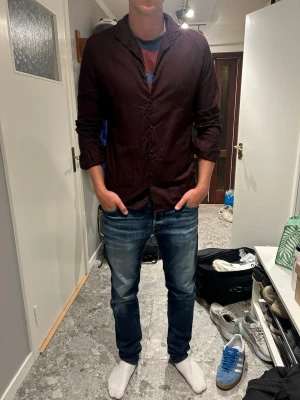 Mörkröd skjorta med knappar - Säljer en mörkröd skjorta från J.Lindbergh med knappar framtill och lång ärm. Skjortan har en enkel, stilren design och normal passform. Perfekt för dig som vill ha en snygg och avslappnad look.