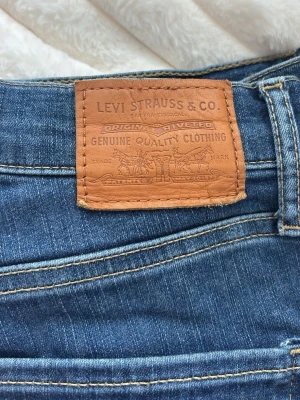 Blå Levi's jeans med klassisk passform - Säljer ett par blå jeans från Levi's med klassisk femficksmodell och snygga kontrastsömmar. Jeansen har en ikonisk läderpatch bak i midjan och röd Levi's-tag på bakfickan. Tillverkade i slitstark denim med skinny modell