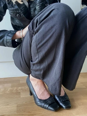 Svarta vintage high heels - Vintage svarta klackar, medelhöga med rosettaktig detalj fram. Väldigt uthålliga skor från Clarks. Hälarna har märken som syns på sista bilden