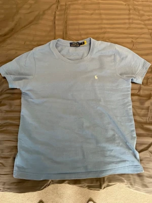 Ljusblå t-shirt från Polo Ralph Lauren - Snygg ljusblå t-shirt från Polo Ralph. Inte använd mycket. Säljer pågrund av den är för liten