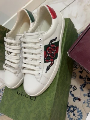 Gucci Ace  - Säljer ett par vita Gucci Ace sneakers i läder med den ikoniska broderade ormen på sidan. Skorna är i 10/10 skick. Kvitto finns och kan skickas vid behov. Priset går o diskutera vid snabbaffär