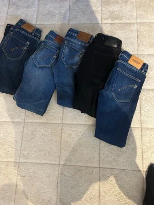 Fem par jeans i olika blå nyanser - Säljer fem par jeans i olika blå tvättar och ett par i svart. Klassisk femficksmodell med kontrastsömmar och läderpatch bak i midjan. Perfekta för dig som vill ha flera stilar att variera mellan. Märket Dondup syns på ett par.
