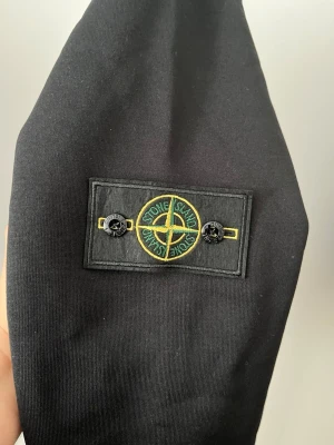 Svart sweatshirt från Stone Island - Svart sweatshirt från Stone Island med den klassiska avtagbara logotypen på ärmen. Prislappen är på den är helt ny, PRISET GÅR ATT DISKUTERA VID SNABB AFFÄR 