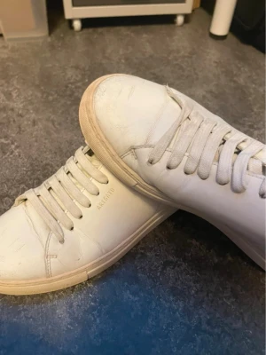 Vita sneakers från Axel Arigato - Stilrena vita sneakers från Axel Arigato med klassisk låg profil och minimalistisk design. Skorna har vita snören, diskret logga på sidan och ovandel i läder. Perfekta för dig som gillar en clean och enkel look. Nypris är ca 2400kr