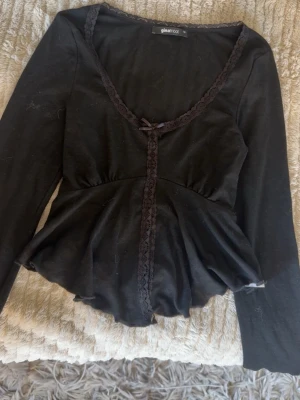 svart topp med volang - jättesöt svart långärmad topp från gina med spetsdetaljer längs ringningen och framtill, jättefint att matcha med jeanskjol!! använd en gång och inga defekter