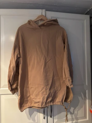 Beige oversized hoodie med dragsko - Säljer en beige oversized hoodie från 157 med huva och dragsko i nederkanten. Hoodien har en mjuk, fleece-liknande insida och långa ärmar. Perfekt för en chill och avslappnad stil.