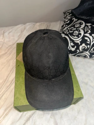 Svart keps med GG-mönster från Gucci - Snygg svart keps från Gucci med det klassiska GG-monogrammönstret låda keps påsen och kvitto finns skriv om du undrar nåt mer äkta såklart 