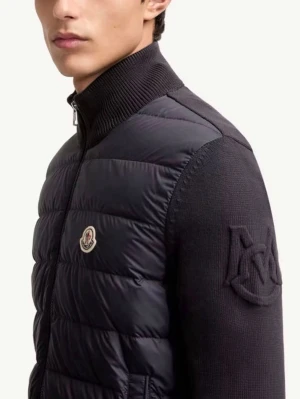 Svart cardiganjacka - Snygg svart cardiganjacka från  med quiltad front och stickade ärmar. Jackan har hög krage, dragkedja och ett stort broderat M på ärmen. Perfekt för lager-på-lager och streetwear.