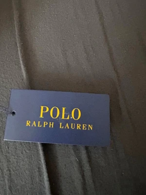 Svarta shorts från Polo Ralph Lauren - Svarta shorts från Polo Ralph Lauren med klassisk logga broderad i vitt på vänster ben. Shortsen har resårmidja med snörning och är tillverkade i mjukt material, perfekta för en avslappnad stil. Jag säljer den för den inte passade mig jag har kvitto köpte den för 5 dagar sedan 