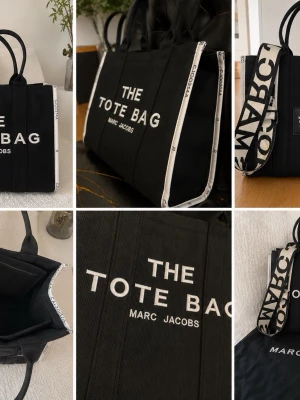 Svart shoppingväska Marc Jacobs märkesväskor totebag - Snygg svart shoppingväska från Marc Jacobs med texten 'THE TOTE BAG' broderad i vitt framtill. Väskan har två handtag och en bred axelrem med logotyp. Tillverkad i kraftigt tygmaterial och har en stilren, boxig form.