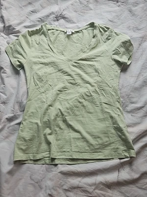 Ljusgrön v-ringad t-shirt - En enkel och fräsch ljusgrön t-shirt med v-ringning och korta ärmar. Tillverkad i mjuk bomull som känns skön mot huden. Perfekt till jeans eller shorts för en avslappnad look.