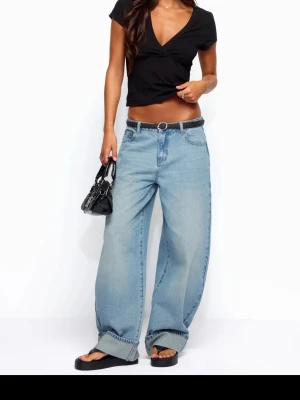 Vida ljusblå jeans med uppvik - Säljer ett par ljusblå jeans från Edited med breda baggy ben som är uppvikta. Jeansen är lågmidjade och har en elegant stil. Jag säljer dom på grund av att dom var lite för långa för mig. Aldrig använda med lappen kvar. Ordinarie pris 1300kr