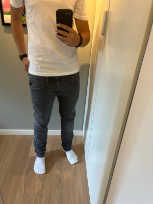 Mörkgrå slitna replay slim fit jeans herr - Säljer ett par mörkgrå slitna Replay anbass slim fit jeans med klassisk femficksdesign och låg midja. Jeansen har smal passform hela vägen ner och är tillverkade i ett stretchigt material för extra komfort. Perfekta för en avslappnad och trendig look. Jeansen har några små slitningar. Modellen är 179cm lång