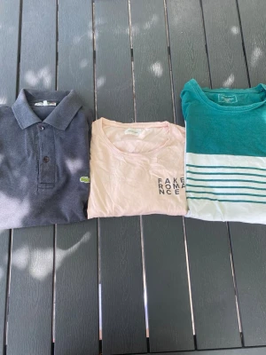 1 pike 2 tshirts paket/sett 📦  - Säljer 1 pike och 2 tshirts i ett sett/ paket.   1. Svart pike från Lacoste, storlek okänd, men sitter som S/M. Någon äldre/vintage modell.  2. Aprikosfärgad tshirt från YourTurn, storlek M, väldigt snyggt tryck på baksidan.  3. Grön vit randig tshirt från dressman, storlek M.  Alla tre tröjor ingår som sagt i köpet.🙌⚜️