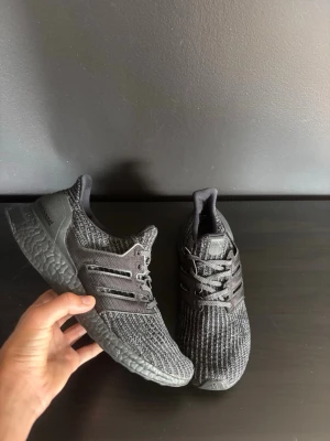 Svarta stickade sneakers - Snygga svarta sneakers med stickad ovandel och matchande svarta sulor. Skorna har en sportig look med snörning och diskreta ränder på sidan. Perfekta för dig som gillar stilrena och bekväma skor i vardagen.  Skick: Bra  Färg: Svart Storlek: 41 1/3 Passar: passar alla Hör av dig vid minsta fråga och priset är såklart inte fast i sten vid snabbt köp!