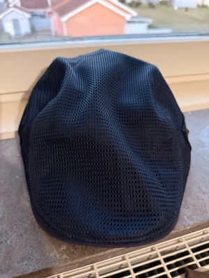 Marinblå keps från Jamont - Snygg marinblå keps från Jamont i meshmaterial som ger en luftig och sportig känsla. Klassisk flatcap-modell med diskret logga på sidan. Perfekt för dig som vill ha en stilren och bekväm huvudbonad med modern touch.